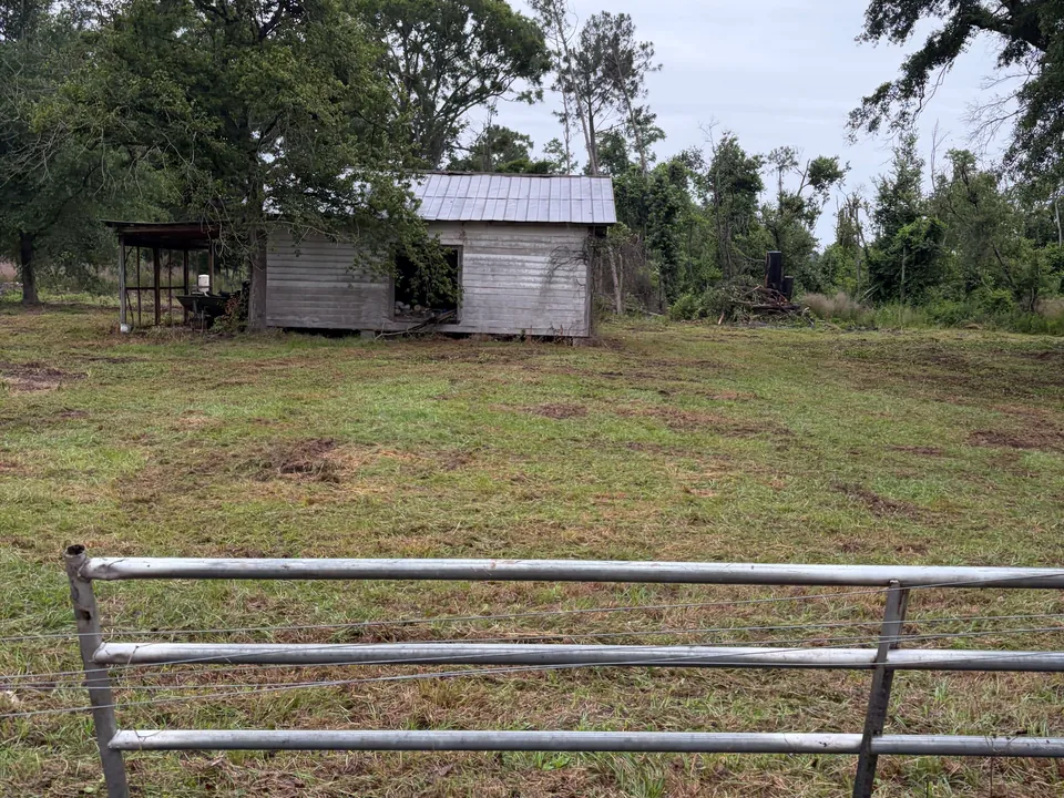 Old shed on a cleared lot behind a metal gate, demolition