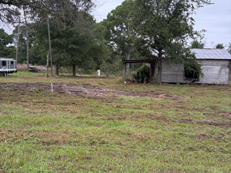 Cleared lot with a stake in the ground near an old shed, site preparation